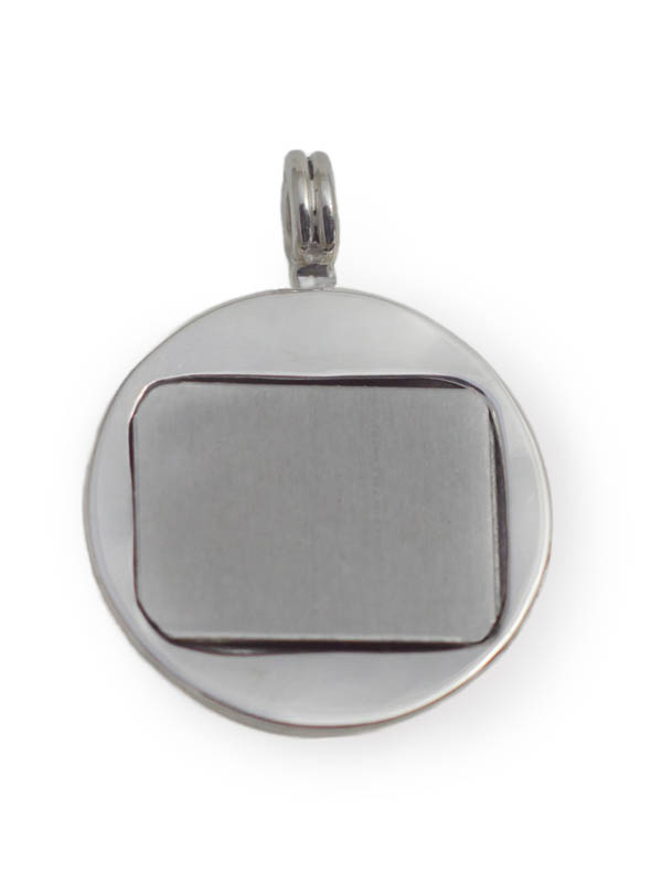 Vor weissem Hintergrund ein rundes, silbernes Amulett, in der Mitte mit einer quadratischen Silberfläche verschlossen