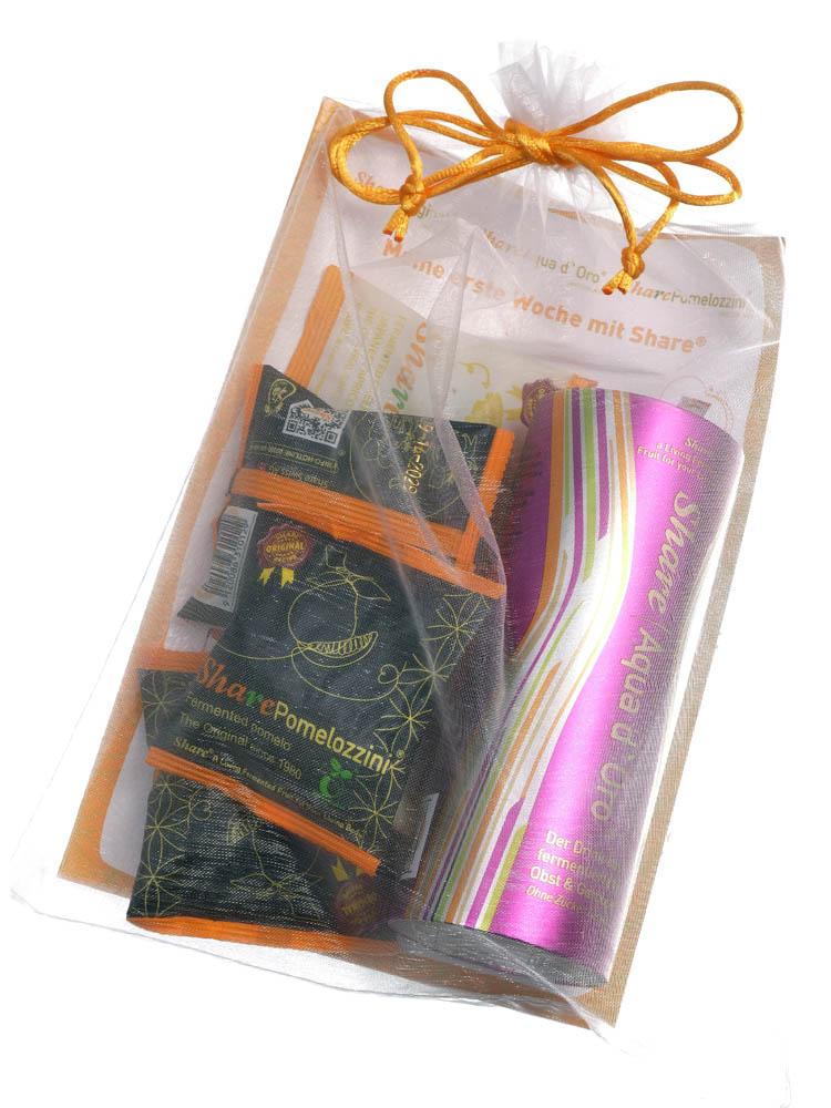 Das Bundle für die erste Woche mit Share wird im Organza-Beutel geliefert Ein weiss-durchsichtiger Beutel mit oranger Schleife enthält dunkelbraune Tütchen und eine pinkfarbene Dose