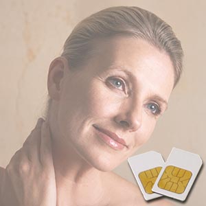 Eine 40jährige Frau mit zurückgekämmtem, eng anliegenden Haar mit einer Hand an ihrem Hals, heller