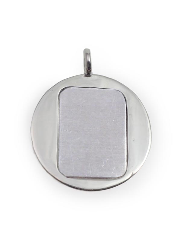 Vor weissem Hintergrund ein rundes, silbernes Amulett, in der Mitte mit einer rechteckigen Silberfläche verschlossen