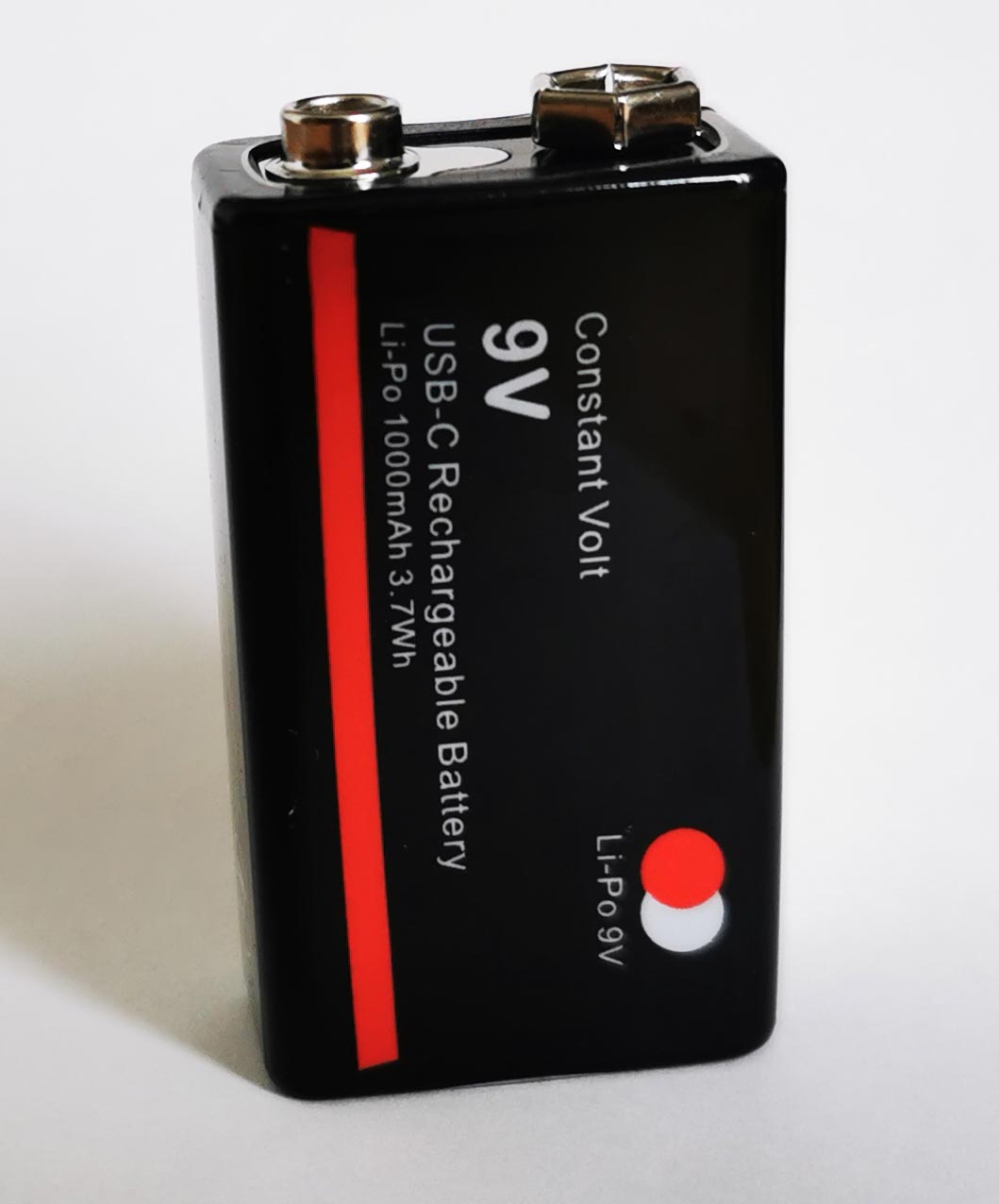Schwarzer, rechteckiger 9 Volt Akku aufrecht, mit rotem Längsstreifen, vor weissem Hintergrund