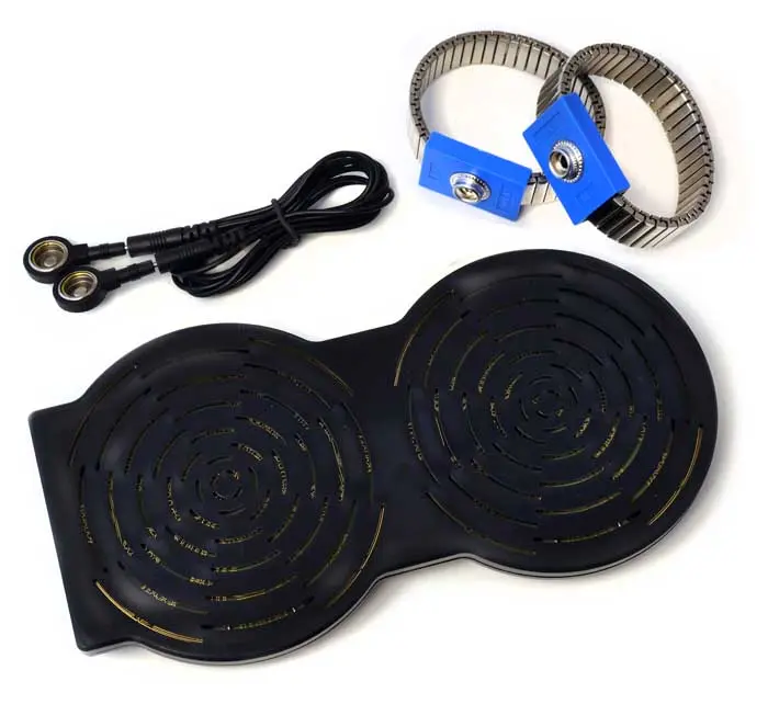 Ein schwarzes Kabel zusammengerollt und quer vor weissem Hintergrund. Daneben zwei silberne Metall-Manschetten mit blauen Verschlüssen und eine schwarze, flache Doppelscheibe