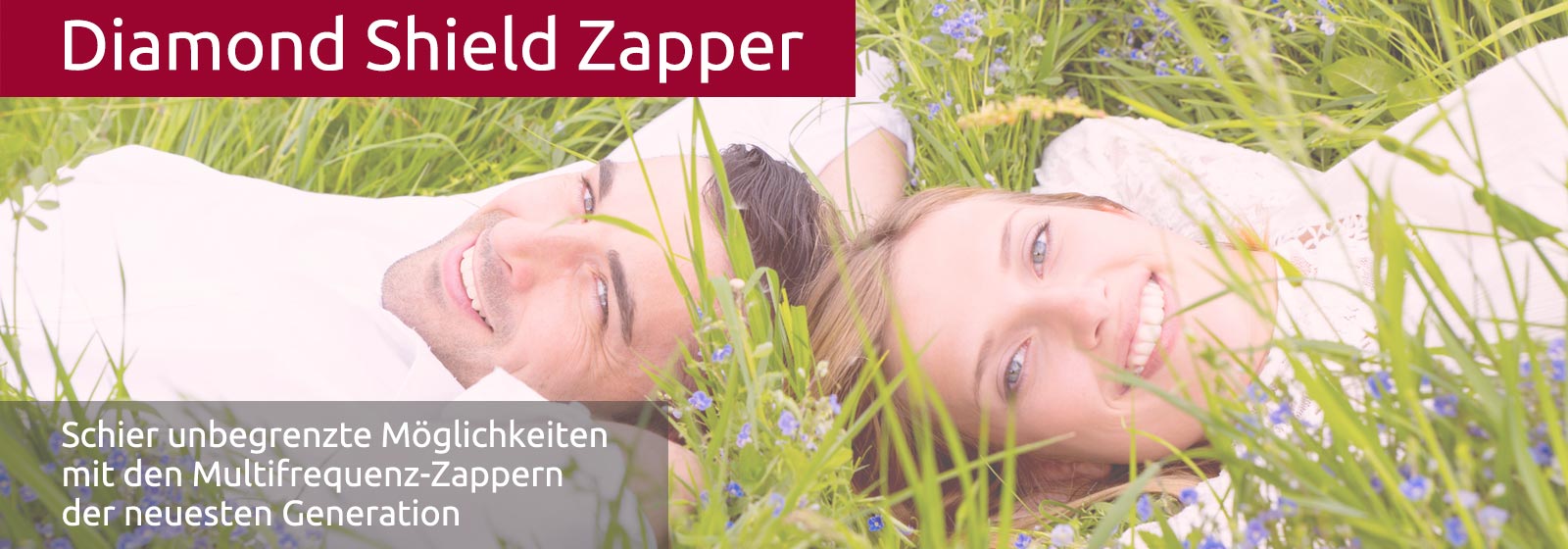 Ein junges Paar (Mann und Frau) liegt Kopf an Kopf im grünen Gras und lacht