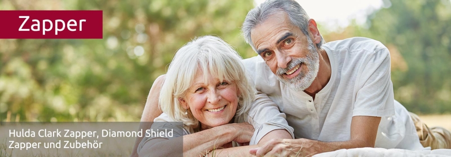 Glückliches, älteres Paar liegt im Gras und lächelt in die Kamera. Sie sind gesund, weil sie den Zapper benützen