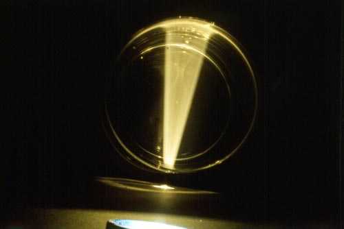 Ein konischer Lichtstrahl scheint durch ein mit Wasser gefülltes Glas